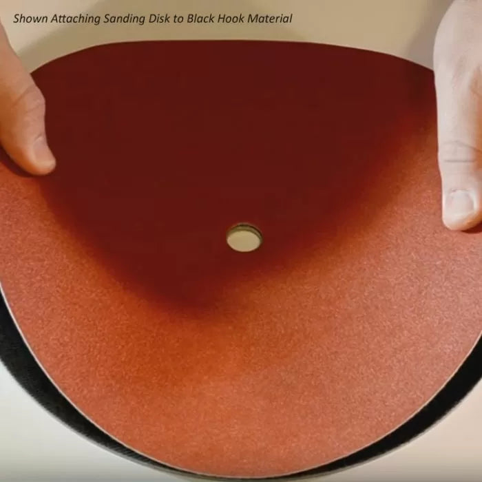 Hands attaching red sanding disk to black hook-and-loop backing for woodworking tools