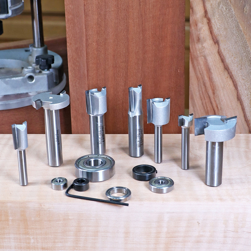 Assorted carbide woodworking router bits and bearings on a wood surface in a workshop