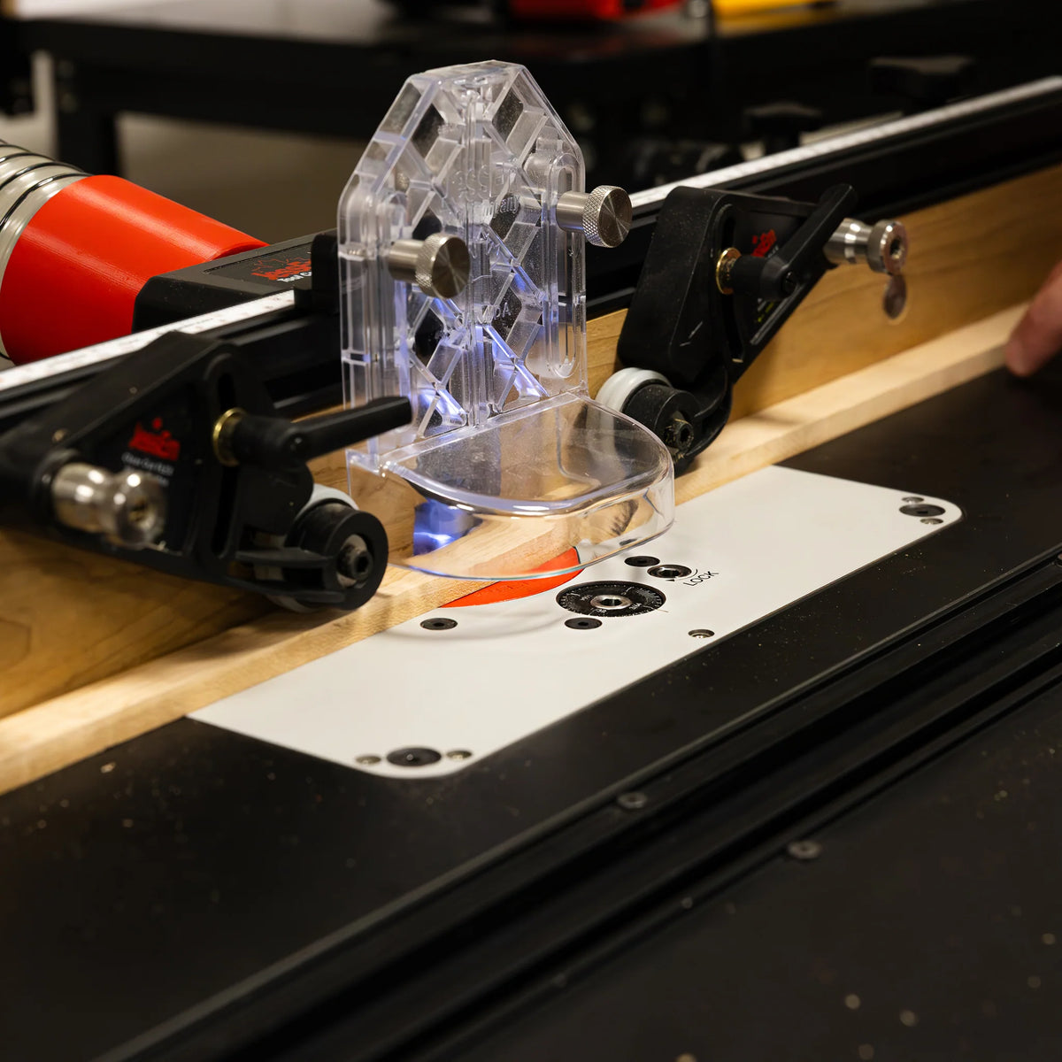Woodworking router table setup with router bit, fence, and clear safety guard in workshop