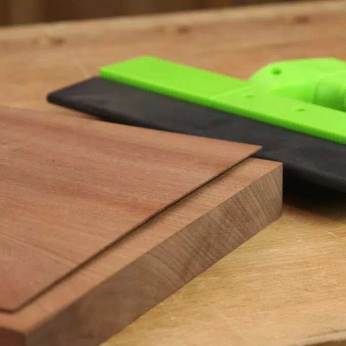 Green push block on wooden workbench with smooth-edged wooden boards for woodworking safety