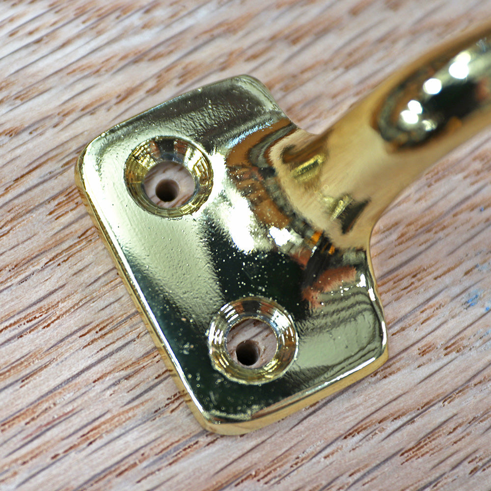 Close-up of a brass woodworking hardware bracket mounted on a wood surface
