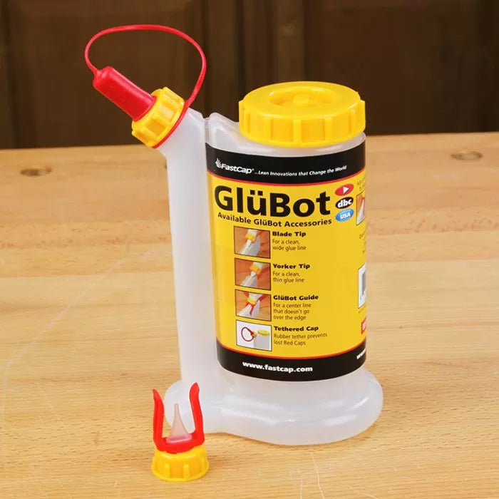 GlüBot woodworking glue dispenser bottle with yellow cap and red applicator on a workbench