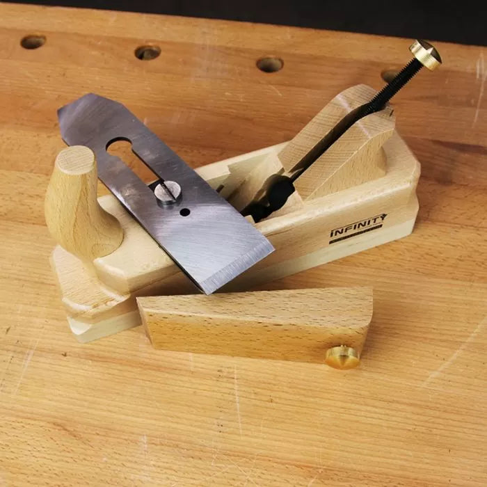 Wooden hand plane with steel blade and brass knob on a woodworking bench