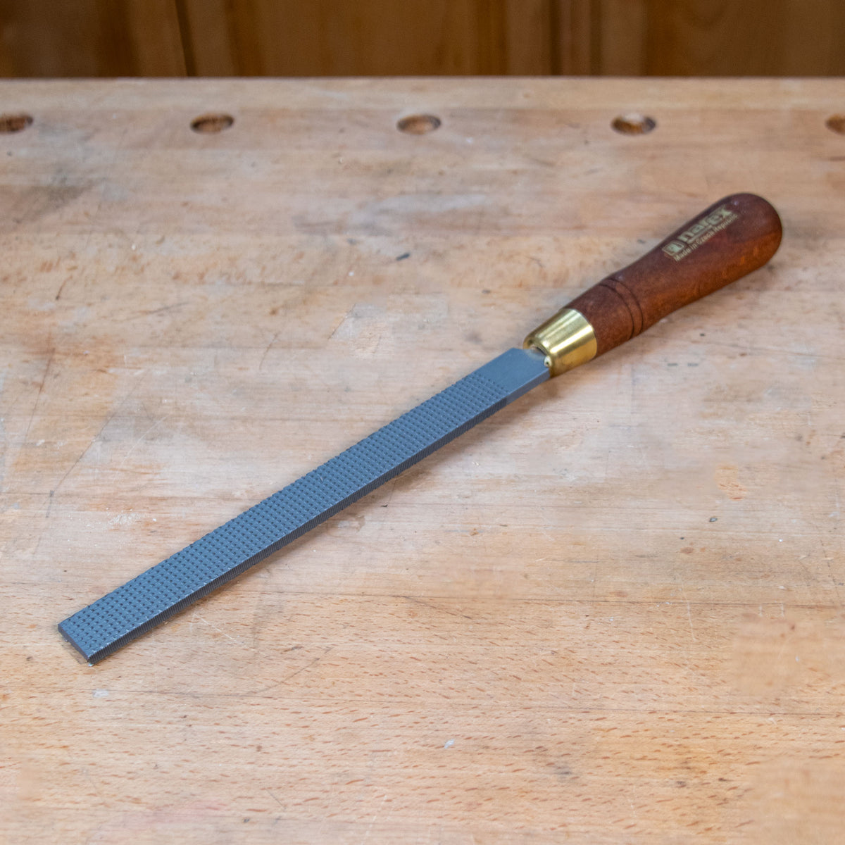 A flat rasp on a wooden work bench.