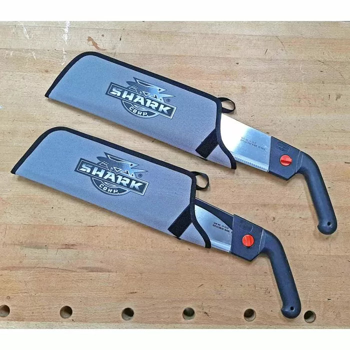 Two Shark Corp Japanese-style pull saws with black handles and blade covers on a wooden workbench.