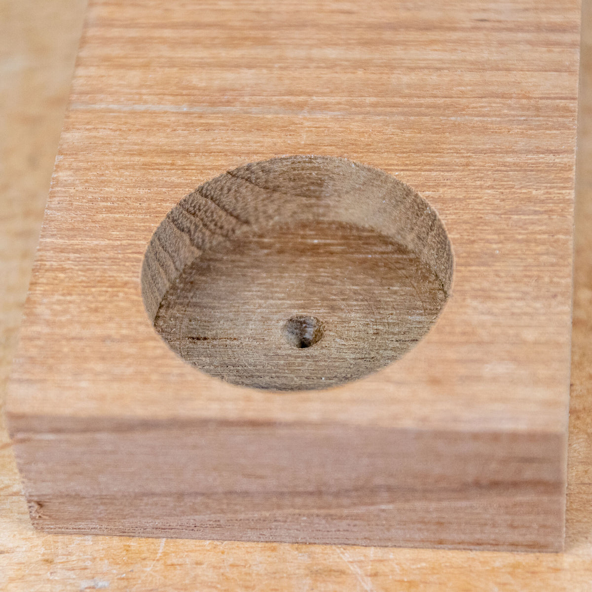 Cleanly drilled hole in a wooden block, showcasing precise woodworking technique