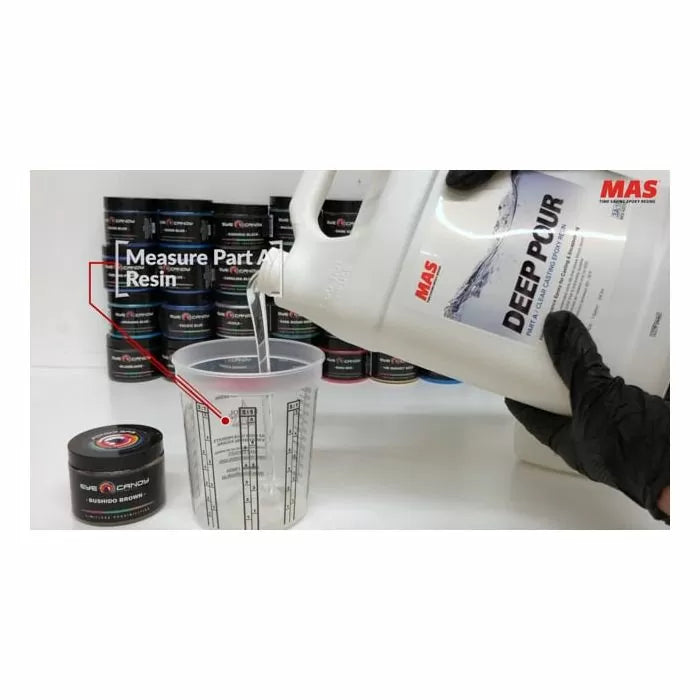 Pouring MAS Deep Pour epoxy resin into a mixing cup, with resin containers in background.
