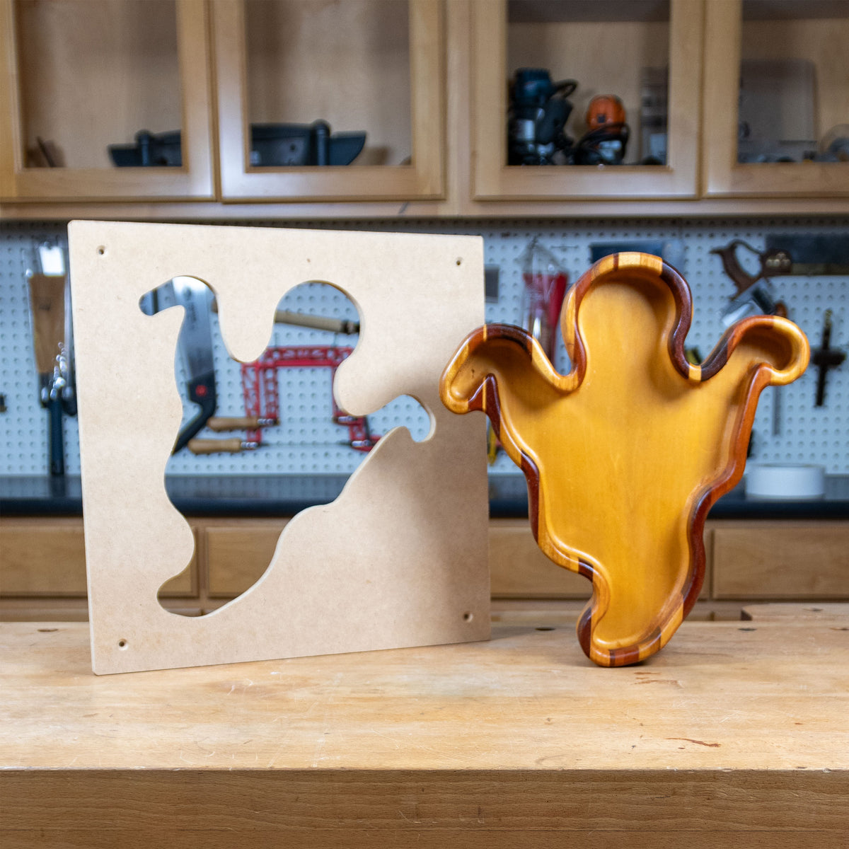 Ghost-shaped woodworking tray and MDF template on workshop bench, wood crafts template.