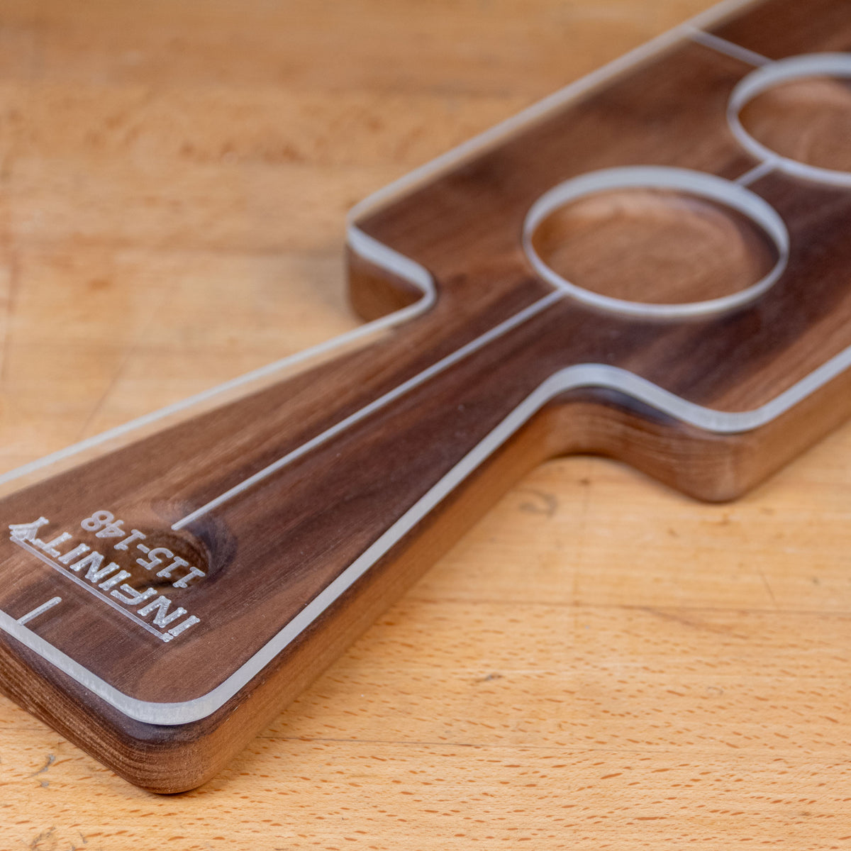Acrylic cutting board template with labeled handle and round cutouts on a wood surface