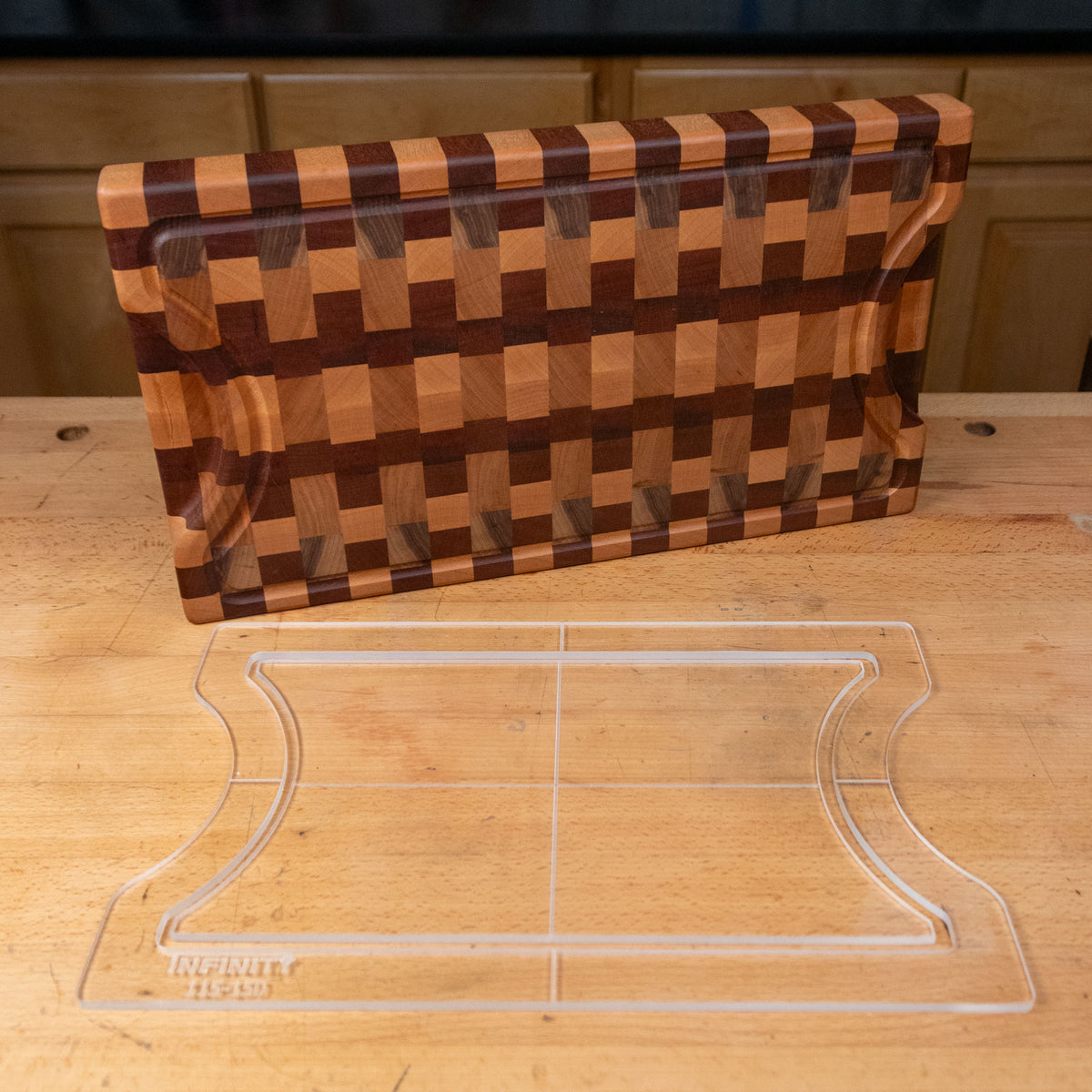 Clear acrylic cutting board template with curved sides on a wood workbench, patterned wood board behind