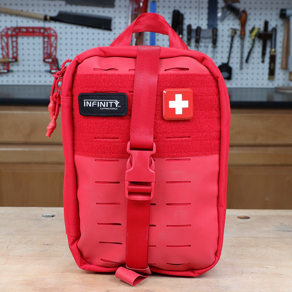 Red first aid kit with handle and buckle on a workbench in a woodworking shop
