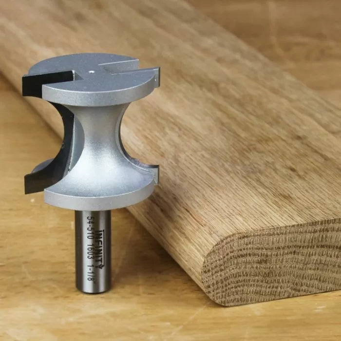 Woodworking router bit next to rounded wooden board on workbench