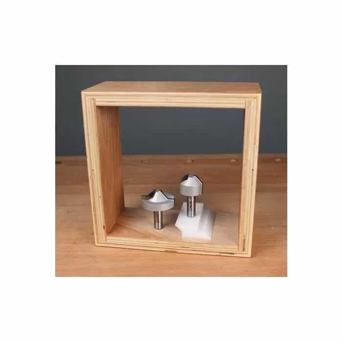 Chamfer router bits displayed on a wooden table in an open wooden box