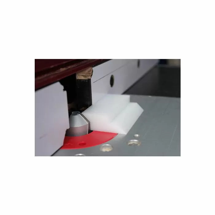 Router table setup with white plastic push block, router bit, and fence for woodworking safety.