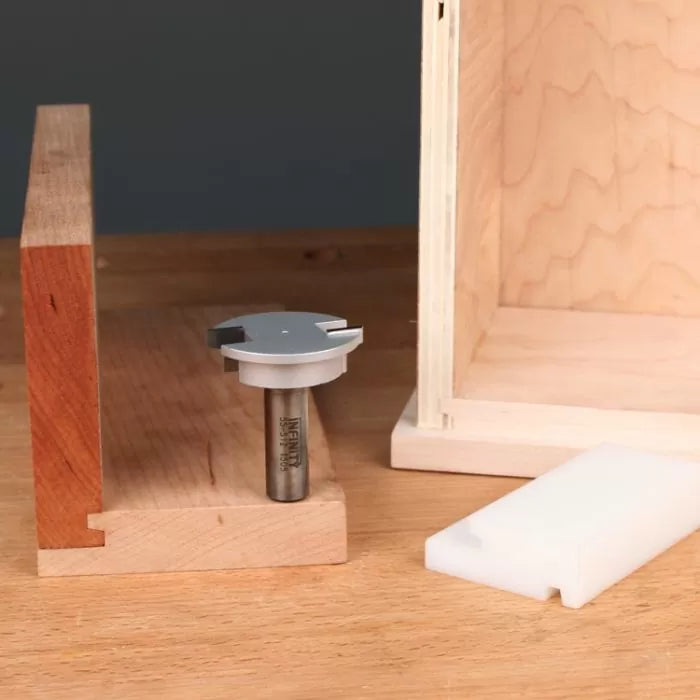 Dado router bit for woodworking on table with cut wood joint and wooden box
