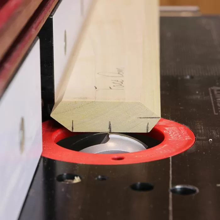 Wood chamfering with router bit on router table, close-up of woodworking process
