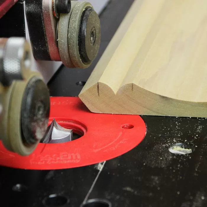 Wood router table with router bit shaping decorative edge on wood board