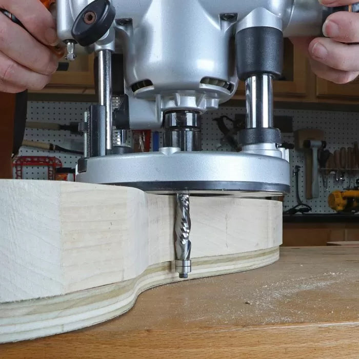 Handheld plunge router cutting curved edge on plywood in woodworking shop