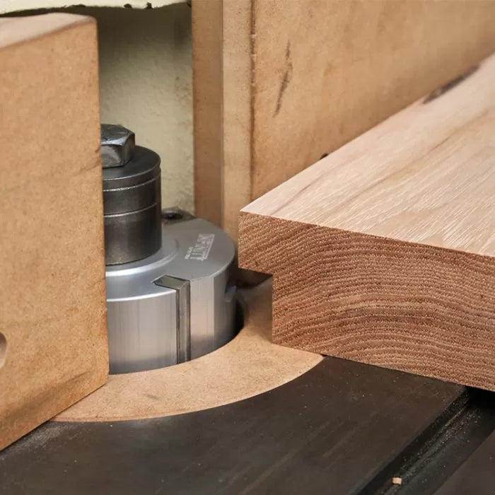 Wood shaper cutter head machining hardwood edge on router table, woodworking tool closeup