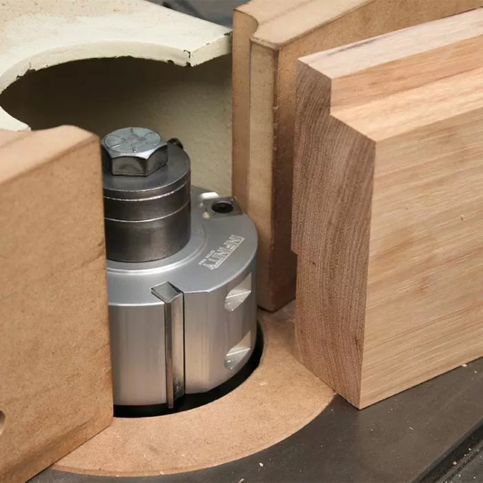 Woodworking shaper cutter head set up with wood pieces on a router table