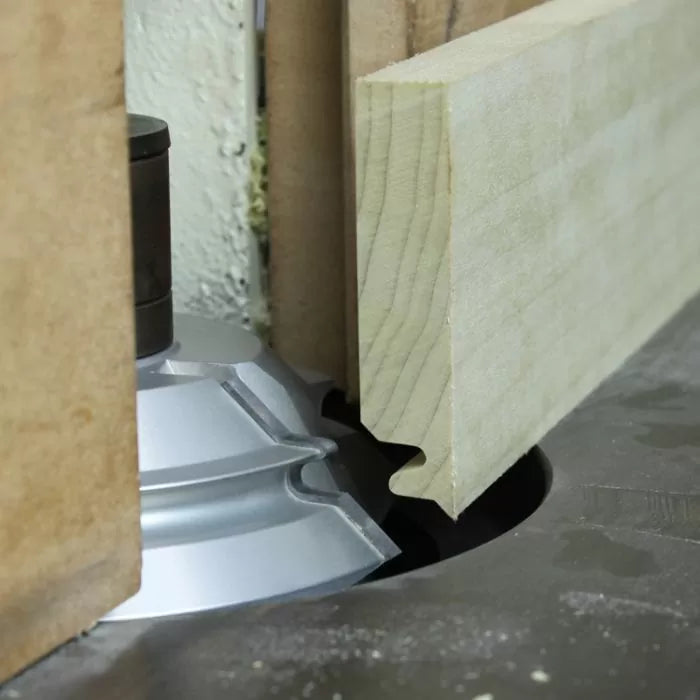 Woodworking router bit cutting a profile on a wooden board in close-up view