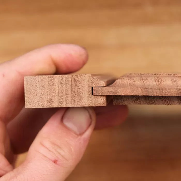 Hand holding interlocking wooden boards with tongue and groove joint for woodworking projects