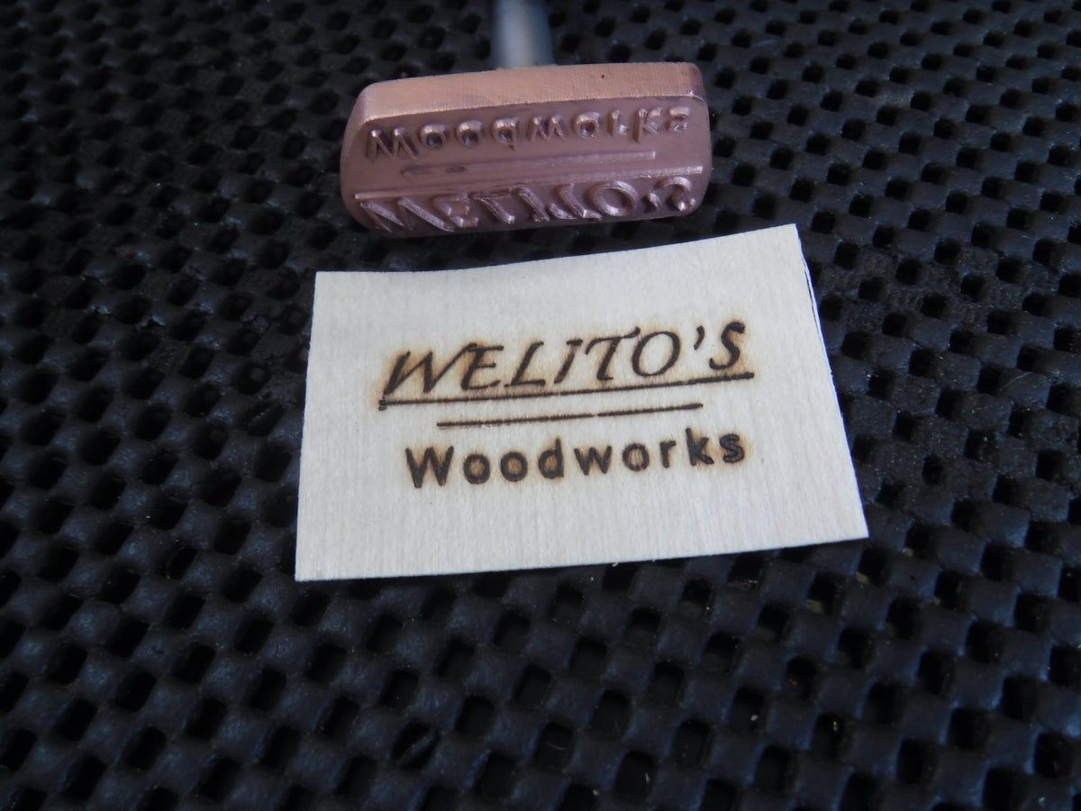 Custom wood branding iron and branded wood tag reading 'WELITO'S Woodworks' on black mat