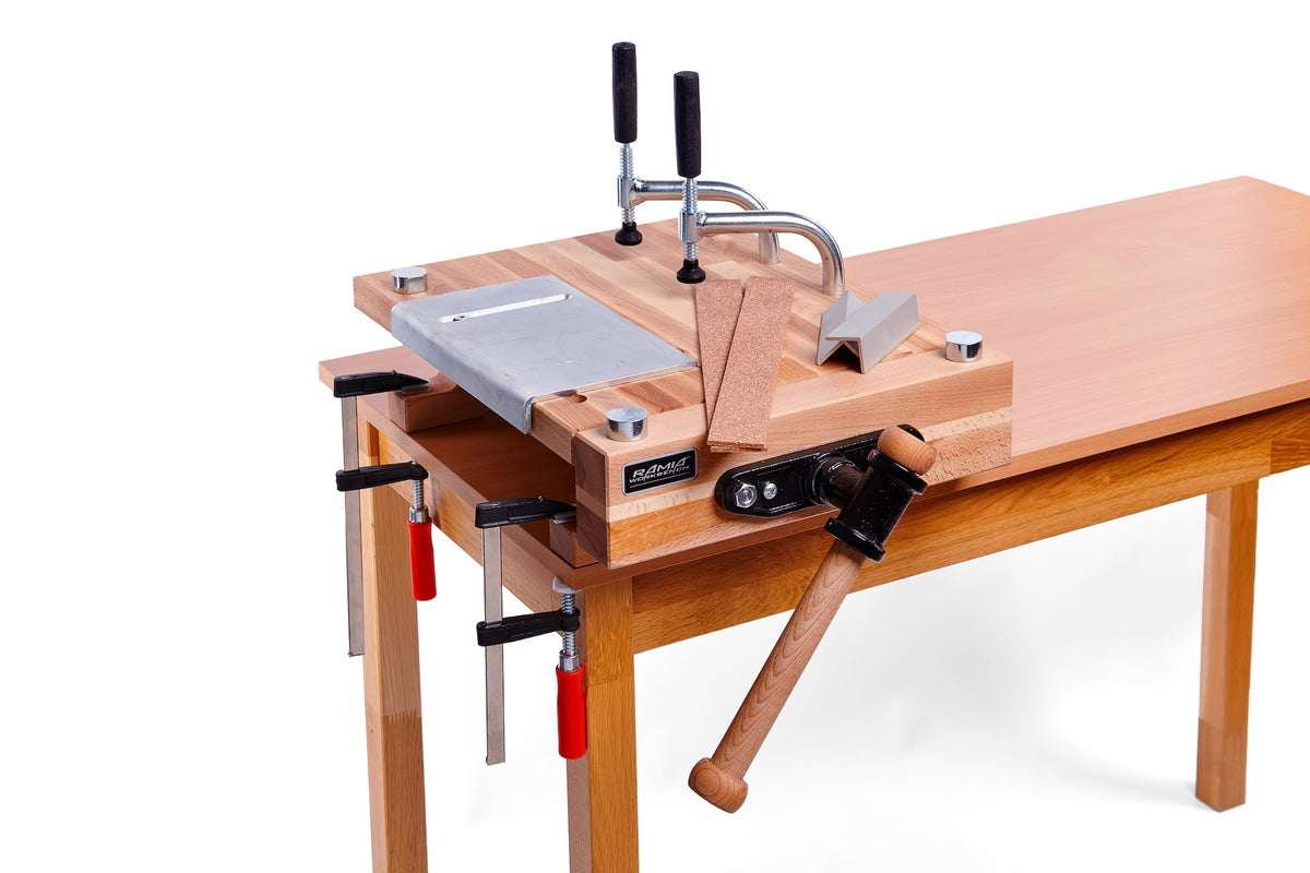A wooden tabletop clamp fixture with metal C-clamps and a wooden miter guide, shown mounted on a wooden workbench against a white background.