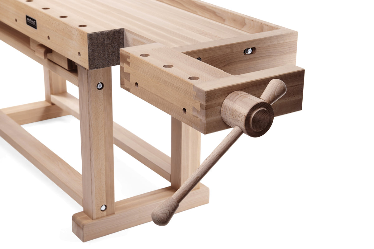 Close-up of a wooden workbench vise with a crank handle, made from light natural wood with darker brown accents, on a white background.