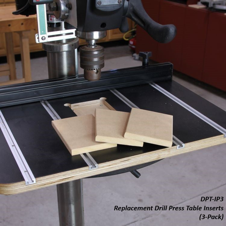 Drill press with replacement table inserts on a woodworking table in a workshop setting