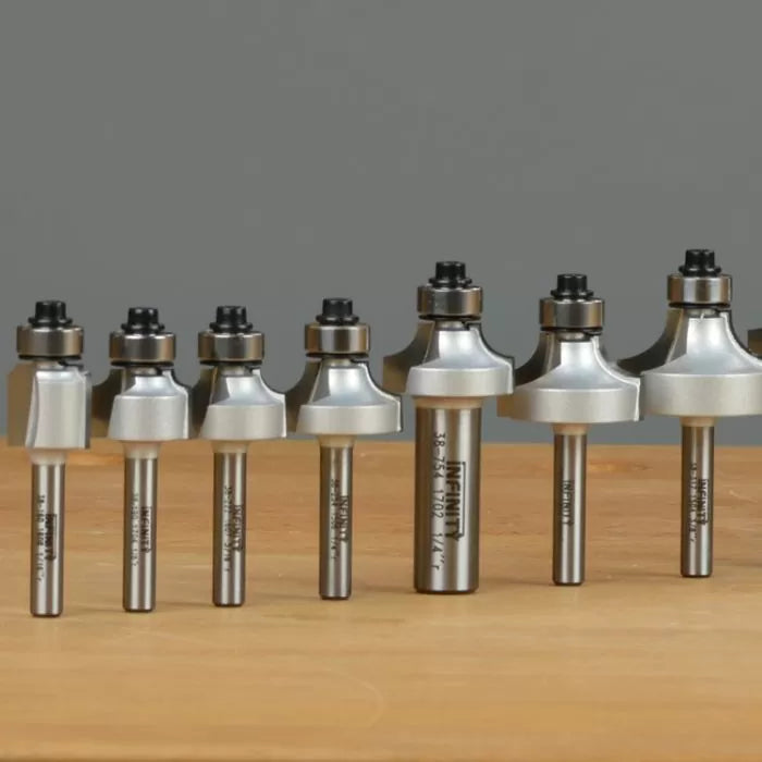 Assorted roundover router bits with bearings arranged on a wooden surface, woodworking tools