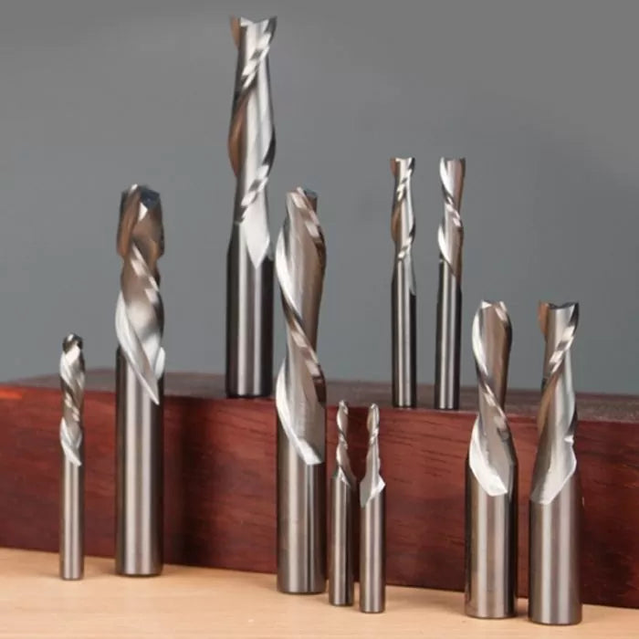 Assorted spiral router bits and end mills for woodworking displayed upright on wood block