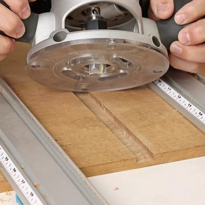 Straight router bit cutting a groove in wood with guide rails and measuring tape