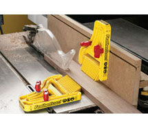 Yellow featherboards holding a board against a table saw fence