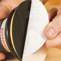 Hand applying a hook-and-loop sanding disc to an abrasive sanding pad