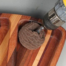 Abrasive scuff ball on a drill sanding the inside of a wooden tray