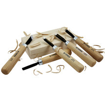 Set of wood-handled carving chisels and gouges surrounded by wood shavings