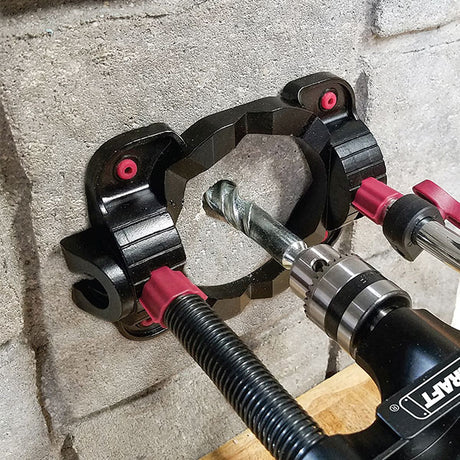 Drill guide clamped around a drill bit against a concrete wall
