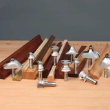 Assorted router bits for woodworking displayed on a workbench with moulded wood samples.