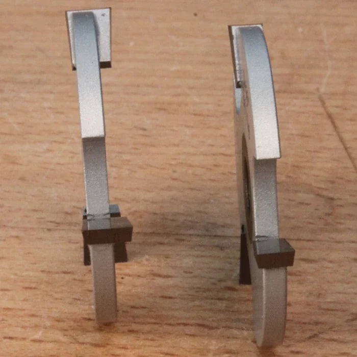 Two woodworking saw blades with carbide tips standing upright on a wooden surface