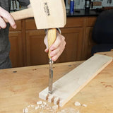 Woodworker using chisel and mallet to cut dovetail joints in hardwood board on workbench