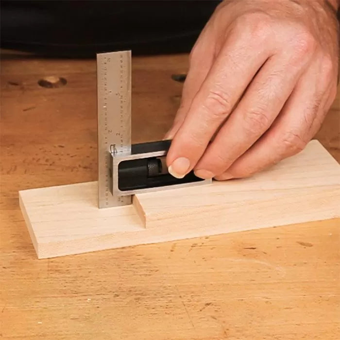 Woodworker using a precision square for accurate woodworking measurements on a wood joint