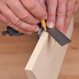 Woodworker using a combination square and pencil to mark a straight line on a wood board