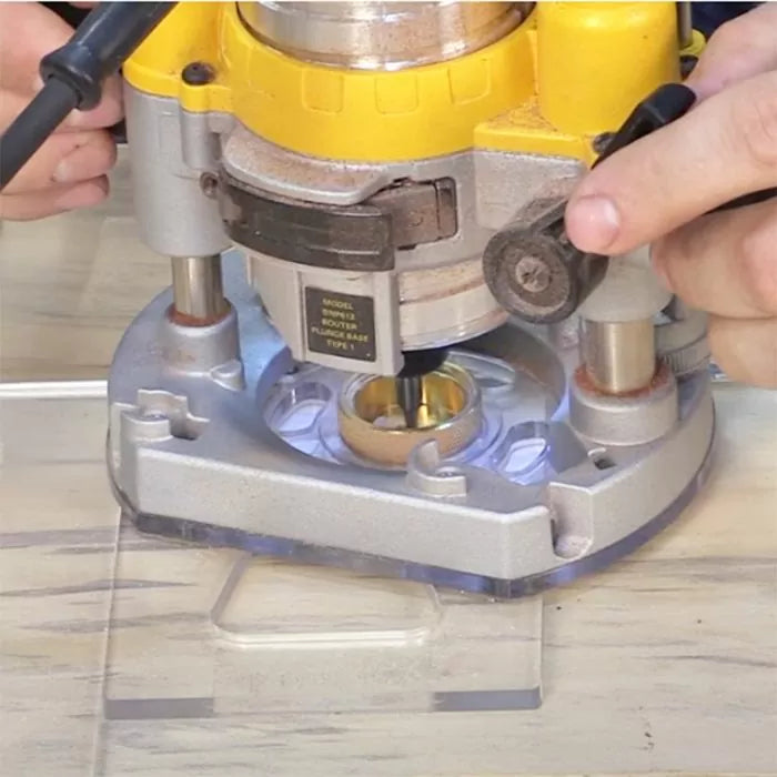 Handheld woodworking router with guide bushing in use on clear base plate