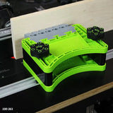 Green woodworking featherboard tool securing wood on a router table for safe cutting