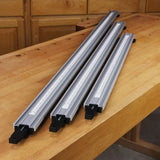 Three aluminum woodworking fence rails with measuring scales on a wooden workbench