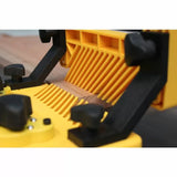 Yellow woodworking featherboard jig securing wood on router table for precise cutting