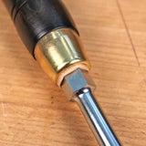 Close-up of woodworking screwdriver handle with brass ferrule on wooden workbench