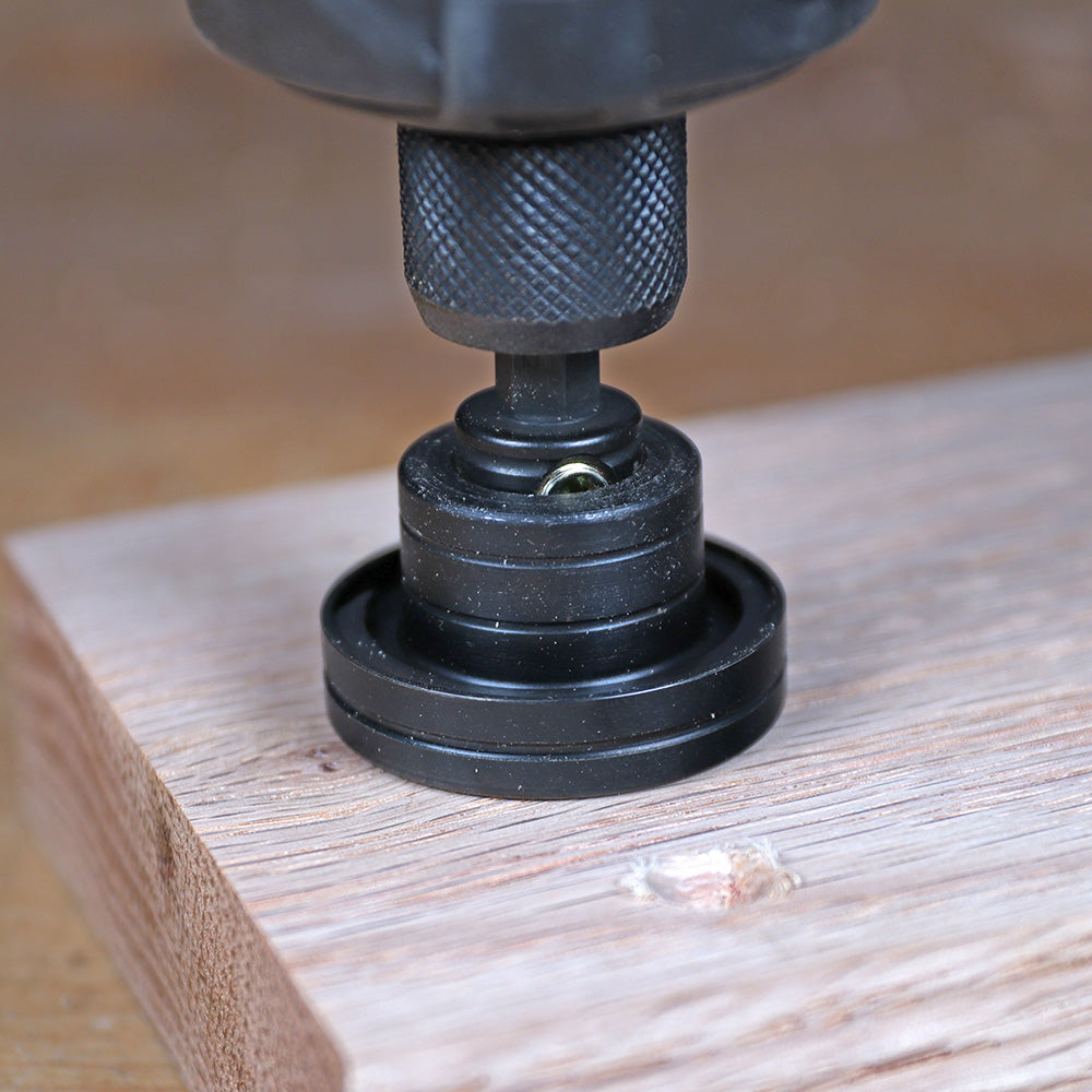 Close-up of a drill-mounted dowel jig aligning on a piece of wood for precise woodworking.