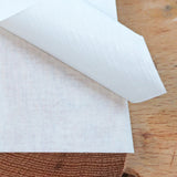 Close-up of adhesive transfer tape being peeled from wood surface on a workbench